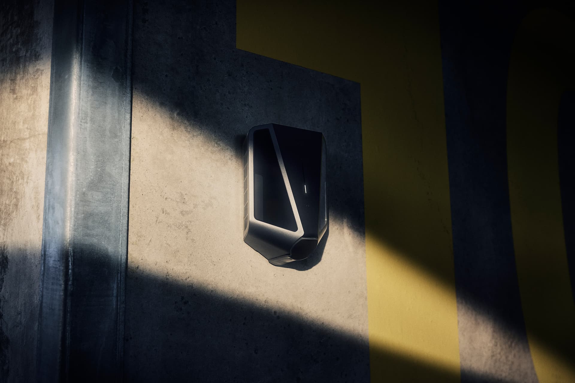 EV-Ladegerät im Halbschatten an einer Betonwand mit gelber Farbe