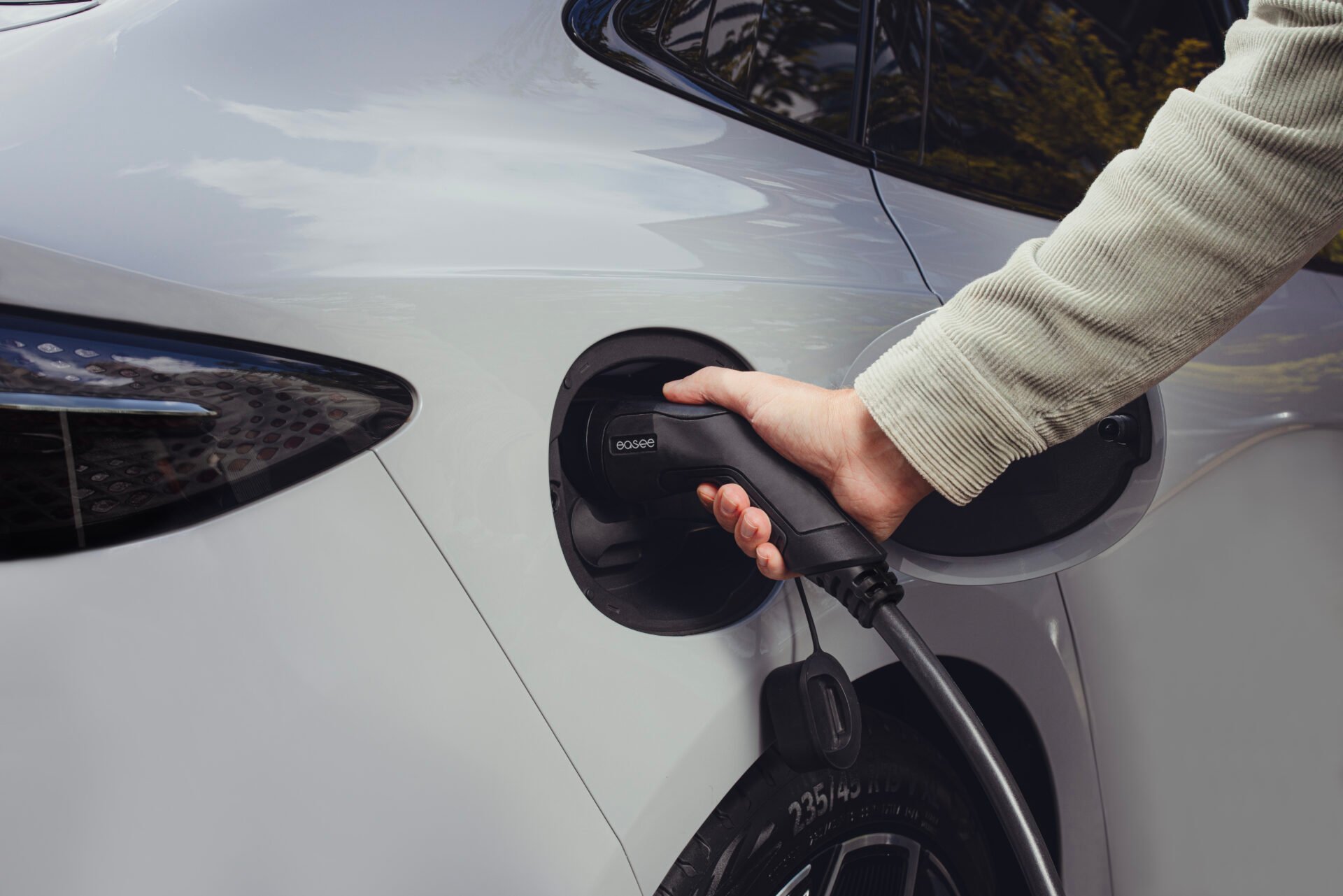Man plugging in EV charger into electrical vehicle to charge