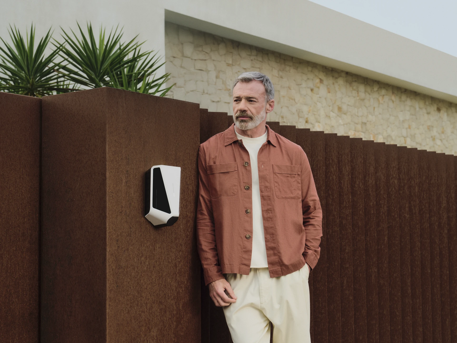 Man next to an Easee charger on an outdoor wall of a modern house